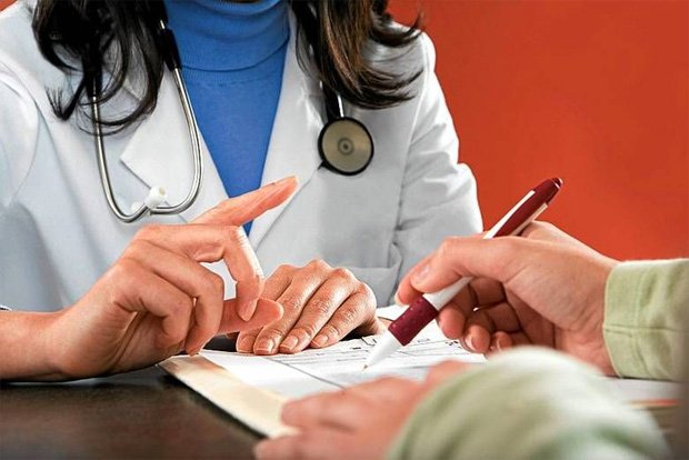 Женщина врач в белом халате дает на подпись пациенту документы