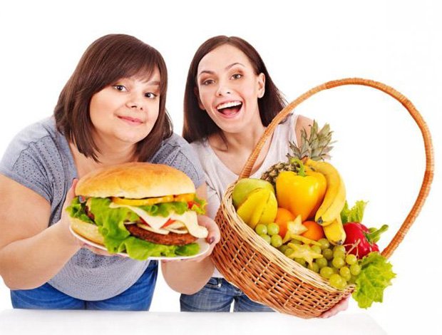 Полная девушка держит тарелку с гамбургером, а худая корзину с фруктами