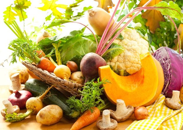 На столе стоит корзина с полезными фруктами и овощами для диеты