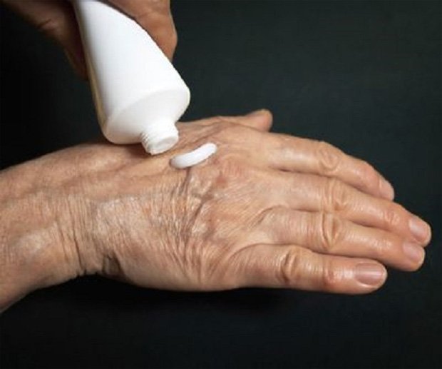 Пожилой человек выдавливает из тюбика лечебную мазь на руку