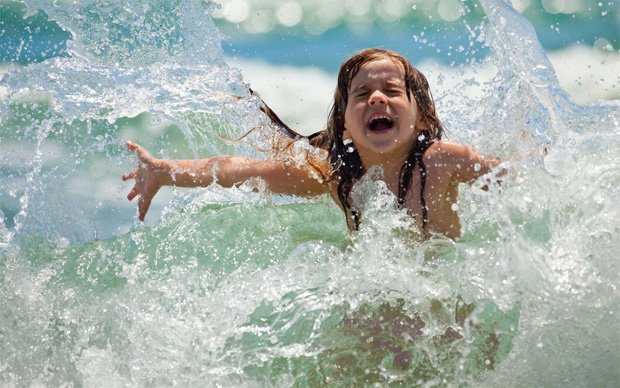 Счастливая девочка зажмурилась от брызг воды азовского моря