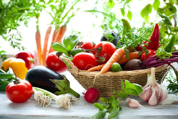 На столе стоит плетеная корзинка с различными полезными овощами