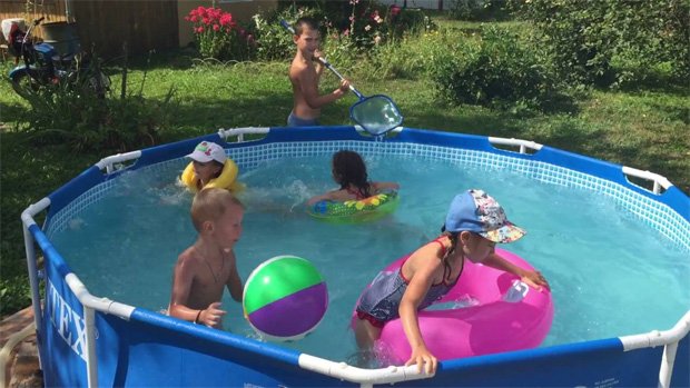 Дети жарким летним днем резвятся в бассейне