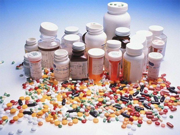 На столе множество баночек из под лекарств и россыпь препаратов