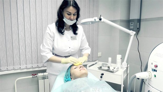 Врач косметолог проводит процедуру фототерапии девушке