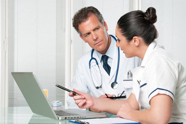 Двое врачей обсуждают диагноз пациента перед ноутбуком
