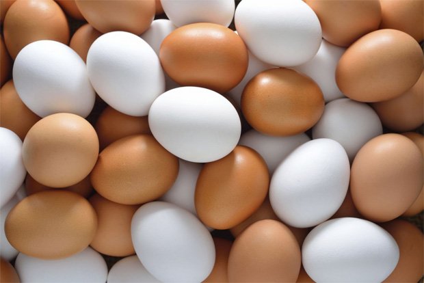 На столе россыпь куриных яиц белого и коричневого цветов