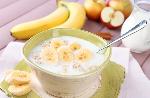 В прозрачной тарелке молочная каша с добавлением бананов и ягод