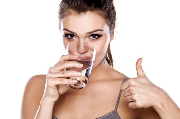 Девушка пьет жидкость из стакана и показывает палец вверх
