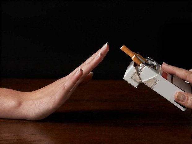Девушке протягивают пачку сигарет и она жестом от них отказывается