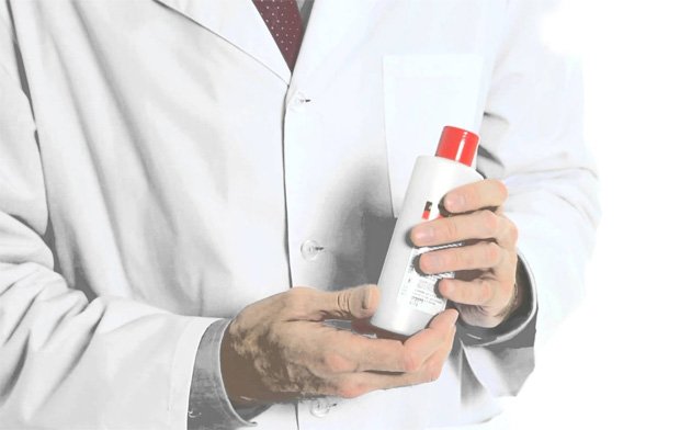 Врач в белом халате держит в руках бутыль с лекарственным препаратом