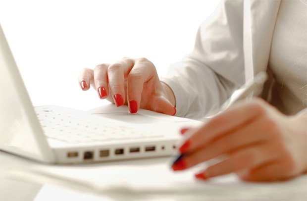 Девушка с красным лаком на ногтях работает за ноутбуком