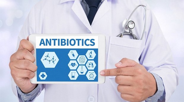 Врач в белом халате держит в руках табличку с надписью Антибиотики