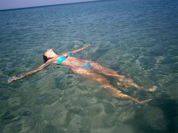 Девушка раскинула руки и лежит на воде черного моря