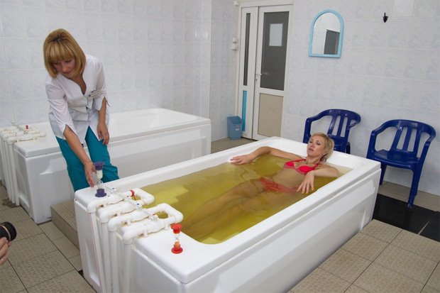 В санатории женщине проводят процедуру принятия ванны с сероводородом