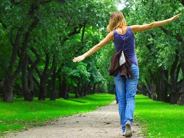 Девушка гуляет по лесу в джинсах и синем топике