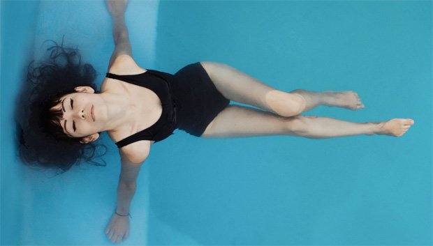 Девушка в черном сплошном купальнике наслаждается в воде