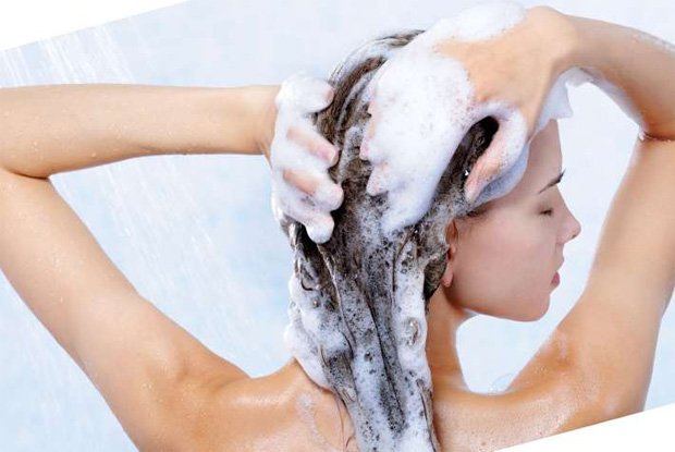 Девушка моет голову пенным лечебным шампунем